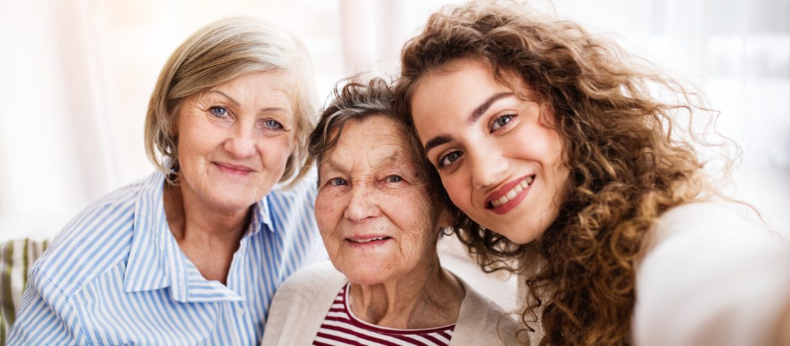 A teenage girl with her mother and grandmother at home. Family and generations concept.